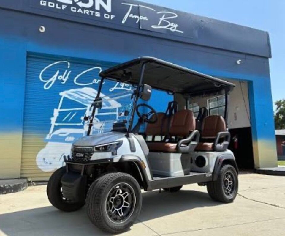 Silver ICON six-passenger golf cart with cognac leather seats parked outside the Icon Golf Carts of Tampa Bay showroom