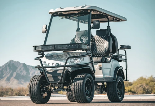 2025 EPIC E40L lifted 4-seat golf cart in white with black diamond-stitched seats, soundbar, and glass windshield — shown on desert road with mountain background
