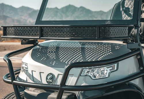 Front view of EPIC E40L golf cart showing signature LED headlight and tubular brush guard against mountain backdrop