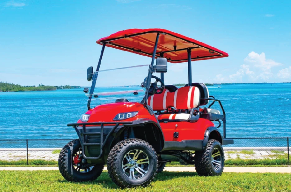 Red ICON i40L lifted golf cart with off-road tires and black-red seating parked on rugged Florida terrain